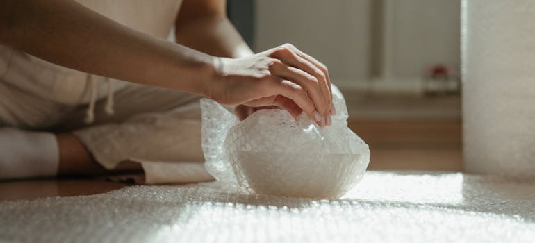 A person wrapping an item in bubble wrap, a shockproof packing material