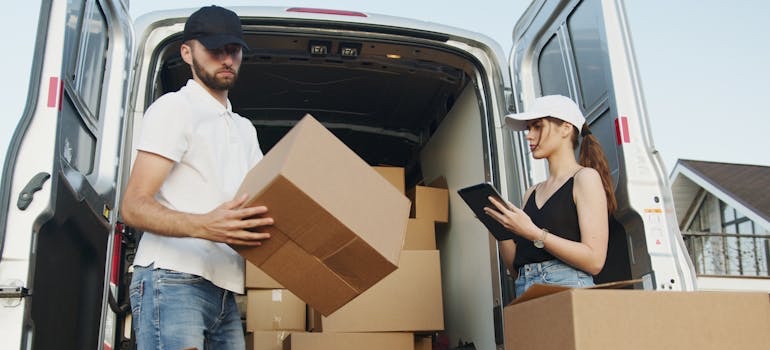 Two people loading moving boxes into a van