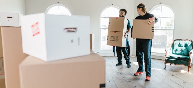 Movers carrying moving boxes into a home in a rural town