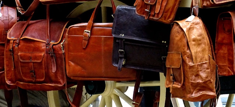 Brown and black leather bags and backpacks hanging on display