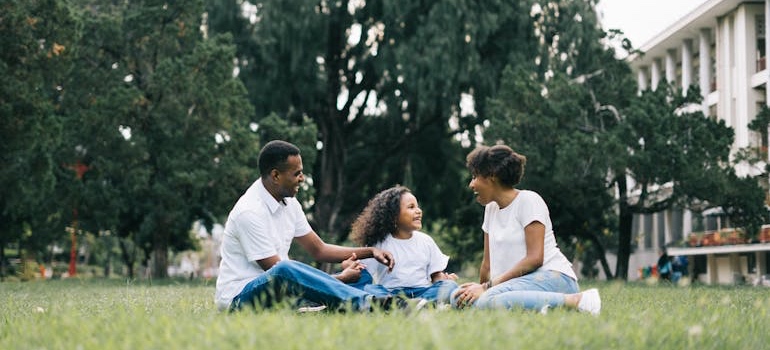 Parents sitting on a park lawn with their daughter