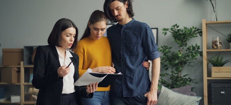 A real estate agent showing a couple around a bright home for sale