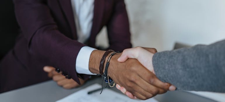 Two adults shaking hands across a desk during a school registration meeting