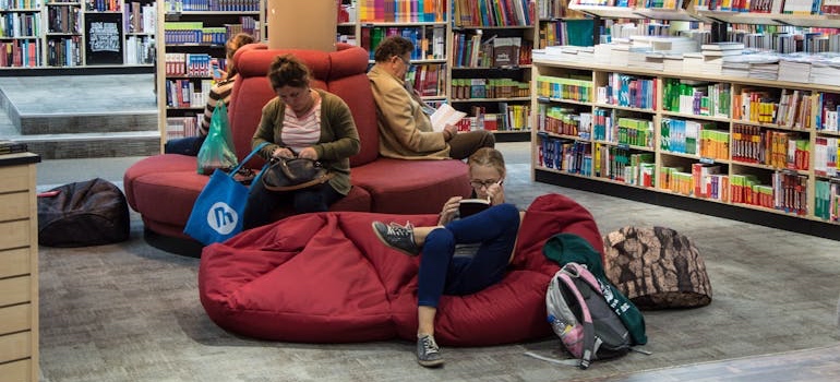 People reading on red couches in a library, one of the best places to meet people after moving to Memphis