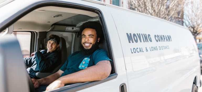 Movers driving a moving van on a residential street