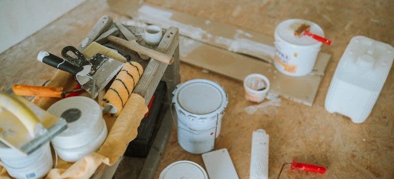 Paint cans, rollers and scrapers on a work surface during a renovation