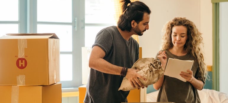 Couple wrapping items in packing paper for an interstate move out of Colorado in winter