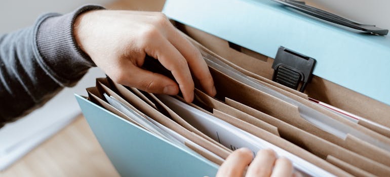 A person flipping through a folder of tax and moving paperwork