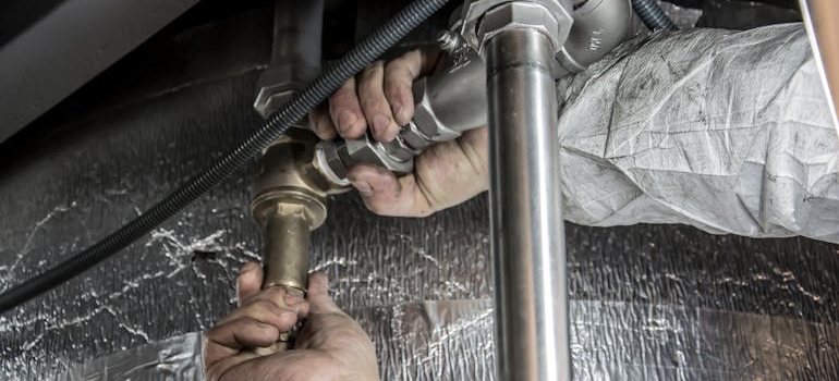 A plumber fixing a pipe under a sink