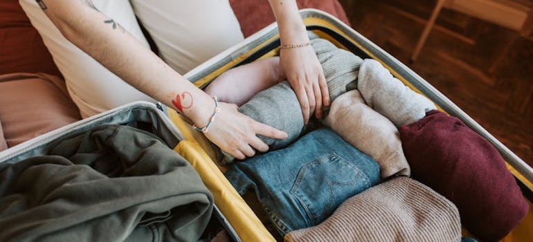 A person packing folded clothes into a box for storage
