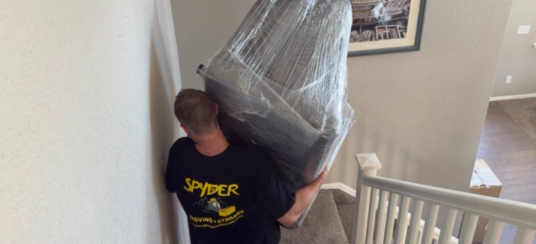 Centennial CO movers from Spyder carrying a wrapped chair down the stairs