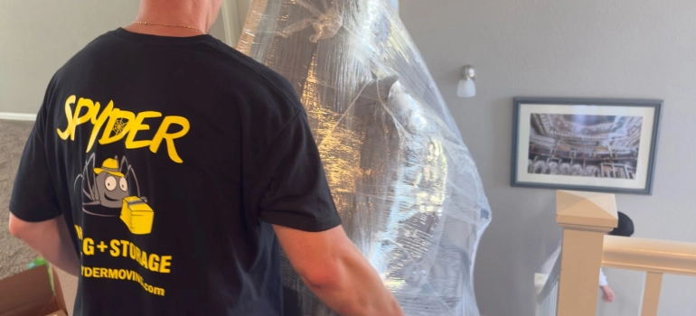 One of our Ocean Springs MS movers carrying a shrink-wrapped piece through a hallway